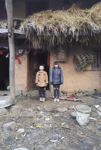 “冰花男孩”王福满和姐姐站在自己的家门口。受访者供图