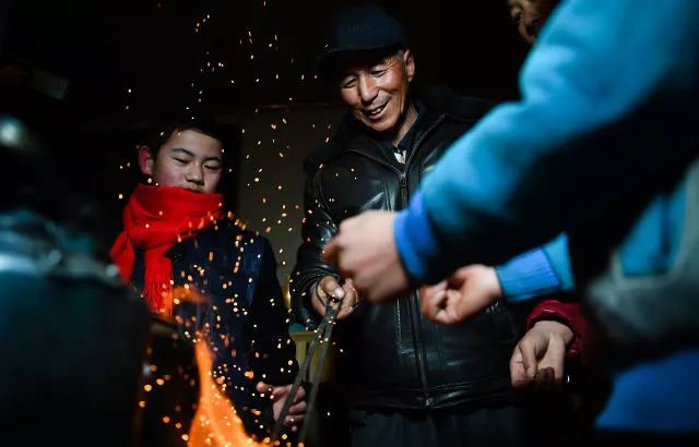 在甘肃省康乐县八松乡新庄村，孙建军（左）到家后和家人一起烤火取暖（2月2日摄）。
