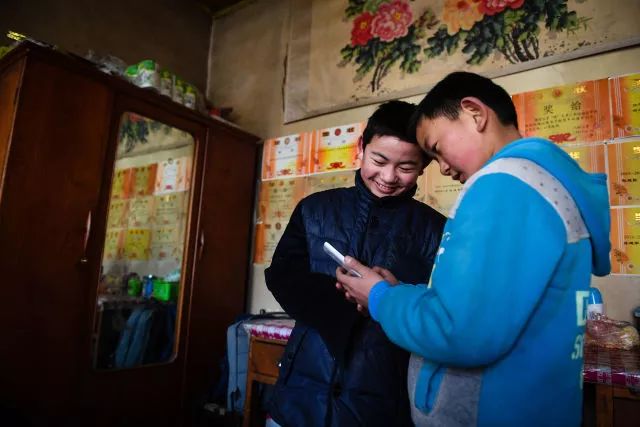 在甘肃省康乐县八松乡新庄村的家中，孙建军（左）和弟弟孙建强一起玩游戏（2月2日摄）。