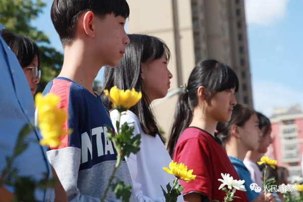 烈士雕塑落成仪式上，沈国良生前所在学校学生手握菊花缅怀烈士。