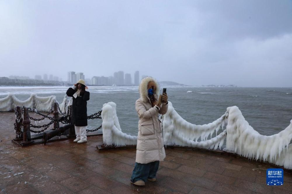 12月21日,两名女子在威海市区海滨观看冰凌美景。近日,连续的降雪低温使山东省威海市区多处海滨出现冰凌美景,吸引众多市民、游客前来打卡、拍照。新华社发(朱春晓摄)