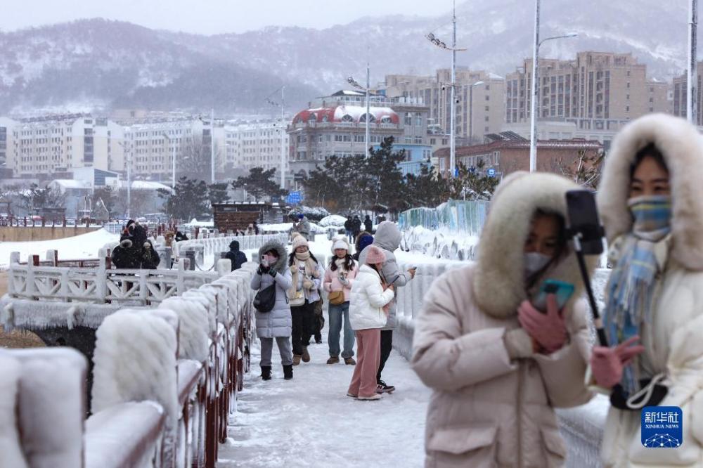12月21日,市民、游客在威海市区海滨观看冰凌美景。近日,连续的降雪低温使山东省威海市区多处海滨出现冰凌美景,吸引众多市民、游客前来打卡、拍照。新华社发(朱春晓摄)