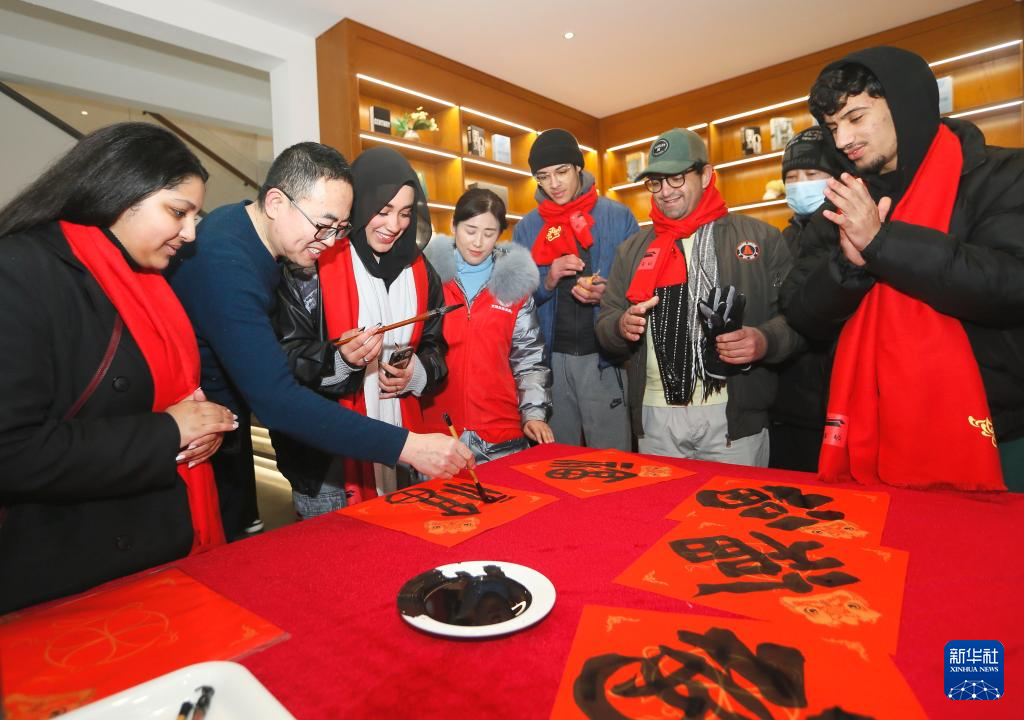 1月18日,“2024春节山东乡村文化旅游节”青岛启动仪式在即墨古城举办,这是书法爱好者与外国留学生一起写福字。春节临近,神州大地年味渐浓。新华社发(梁孝鹏 摄)