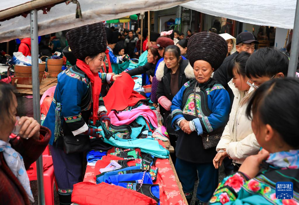 1月18日,顾客在湖南省凤凰县山江镇集市上选购苗服。春节临近,神州大地年味渐浓。新华社记者 张铖 摄