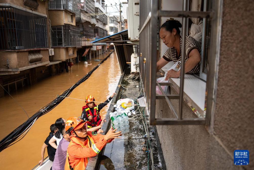 7月2日,在平江县大桥西路附近,消防员给被困群众运送物资。