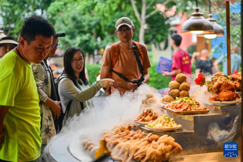 在伊犁哈萨克自治州伊宁市六星街，游客购买当地美食（7月28日摄）。