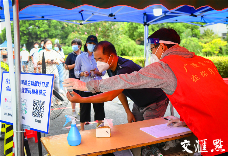 8月14日，扬州市广陵区青年志愿者在社区核酸检测采样点为居民提供温馨服务。肖勇摄