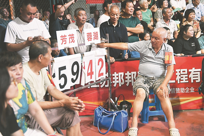 常州横山桥镇新安村健身广场，60多岁的村民刘泉焕（右）、刘裕德在球场边手动记分。作为30多年的资深球迷，他俩主动请缨每天无偿志愿服务联赛。 记者 余萍/摄