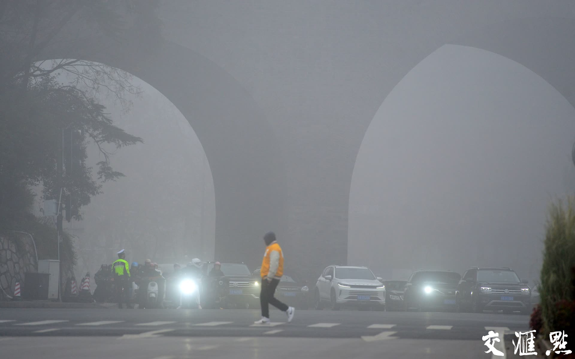 1月4日，一位行人快速通过马路，身后的南京古城墙在大雾中若隐若现。
新华日报·交汇点记者 郎从柳摄