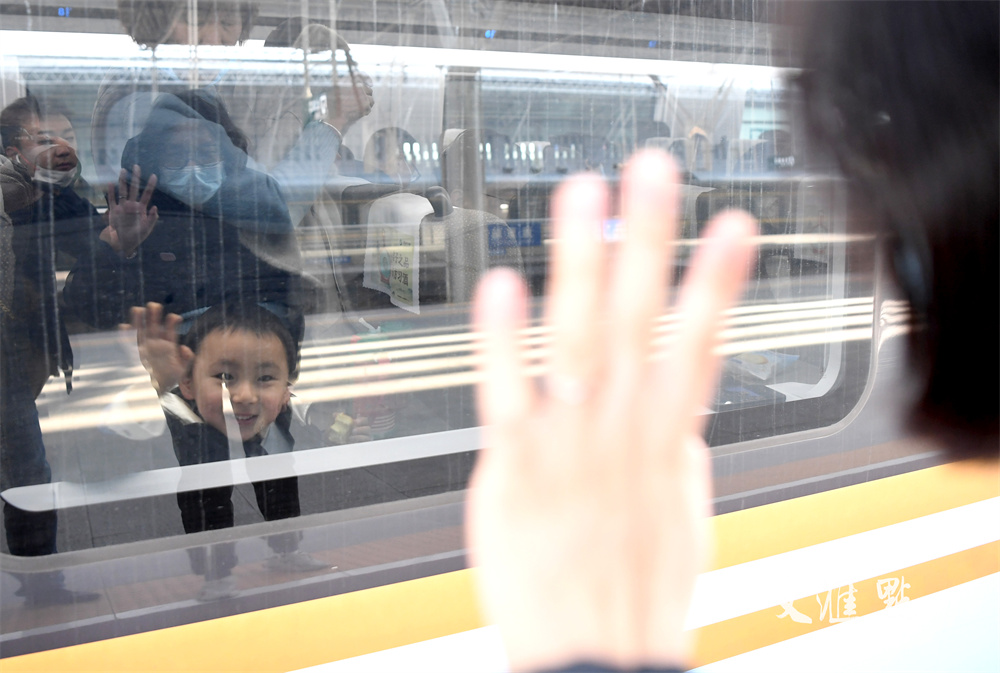 2024年1月26日，在南京火车站，一位年轻妈妈与先行返乡的孩子隔着车窗挥手惜别。