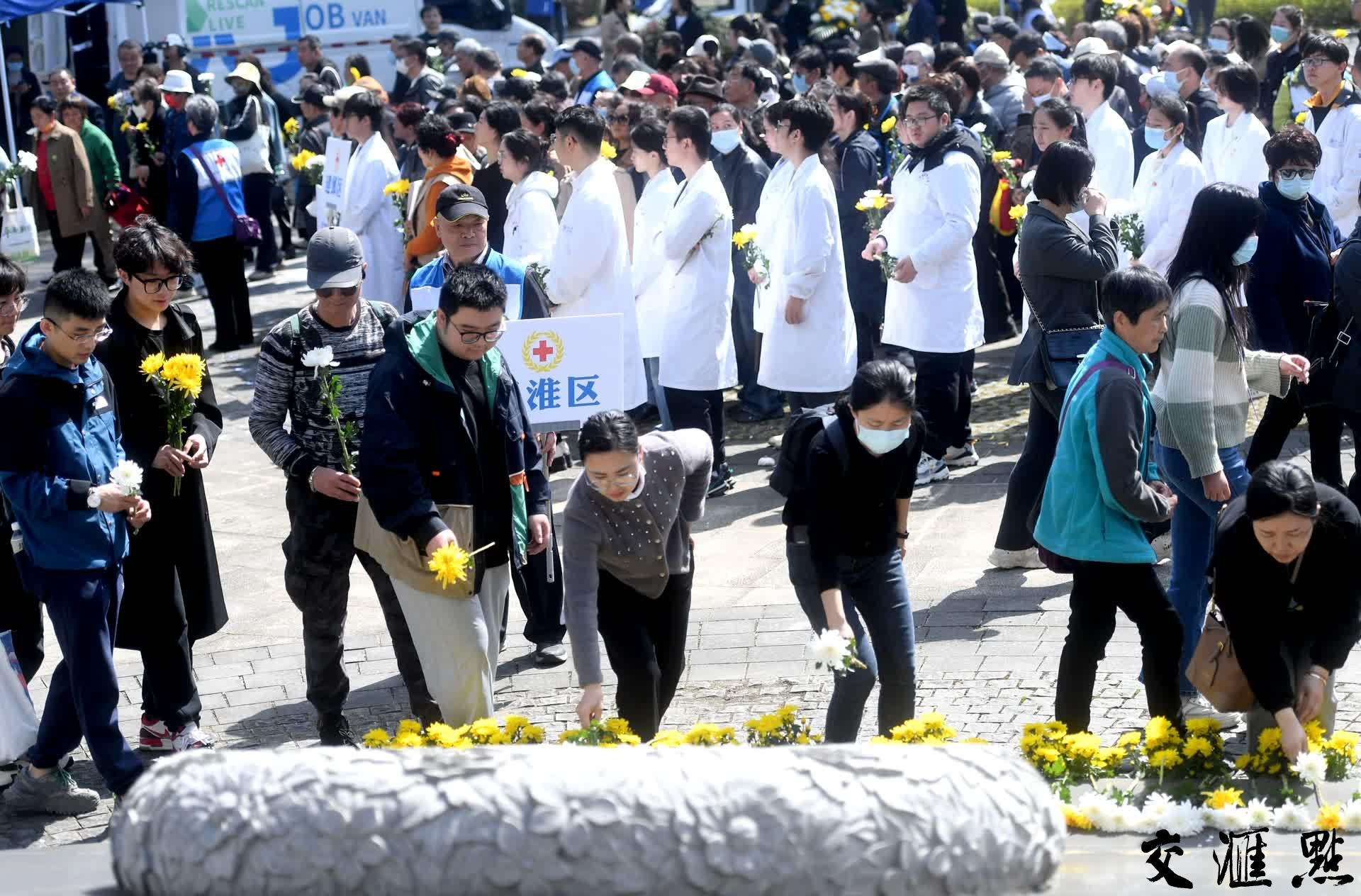 近千名参加活动的捐献者家属代表、器官移植受益者家属代表和志愿者代表手持鲜花，在低回的音乐声中默哀致敬，表达对遗体和人体器官捐献者的追思和敬意。