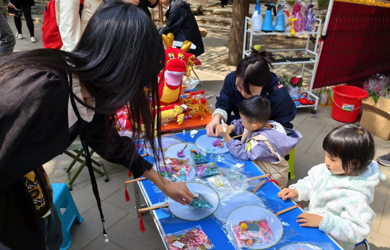 北京陶然亭公园开设的陶然市集上,小游客们正在体验画扇面。人民网记者 乔业琼摄