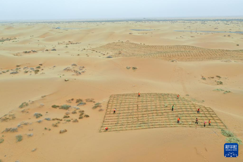 4月27日，治沙工人用稻草在沙漠中扎草方格（无人机照片）。