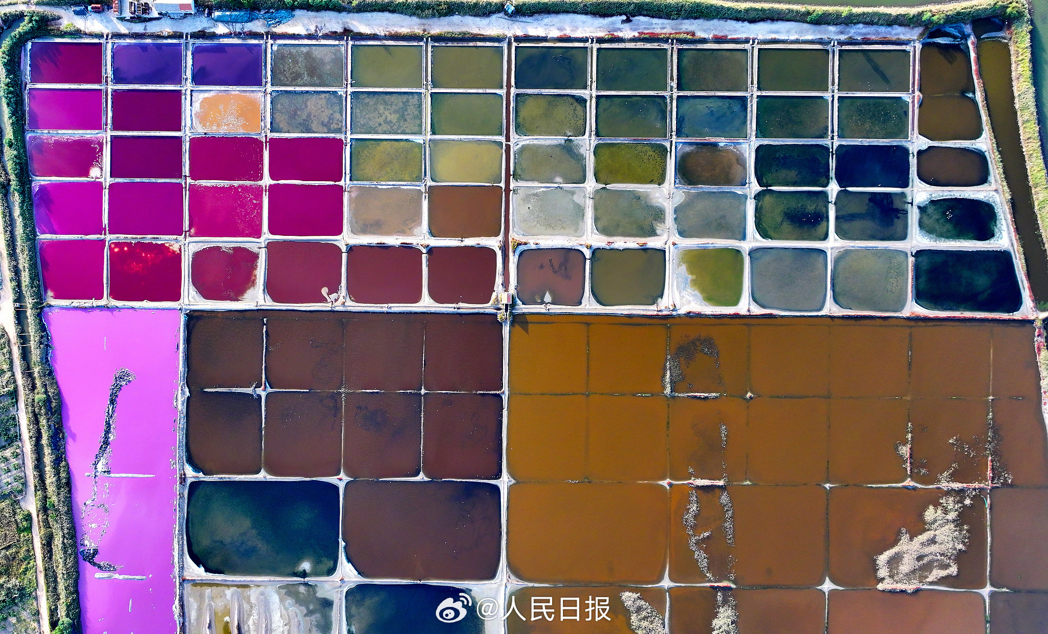 近日，山东荣成，港西镇朝阳港一处盐田，呈现出高饱和度色彩，像是被大自然打翻的调色盘，又如同神秘的大地呈现的一片艺术画布，形成了一道靓丽的风景线。