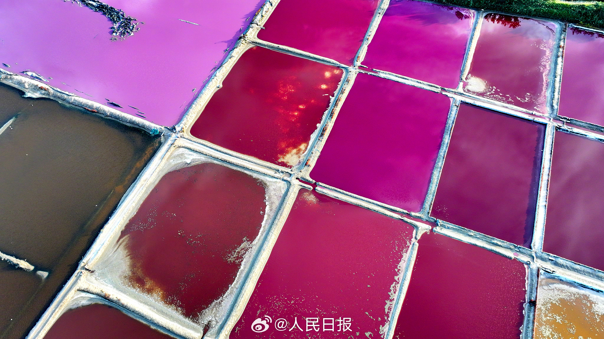 近日，山东荣成，港西镇朝阳港一处盐田，呈现出高饱和度色彩，像是被大自然打翻的调色盘，又如同神秘的大地呈现的一片艺术画布，形成了一道靓丽的风景线。