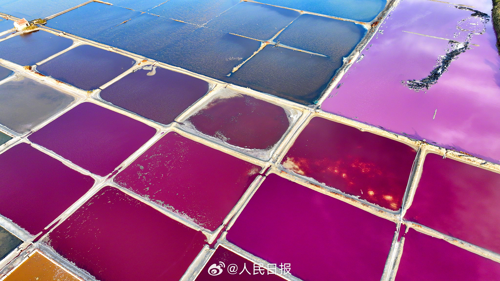 近日，山东荣成，港西镇朝阳港一处盐田，呈现出高饱和度色彩，像是被大自然打翻的调色盘，又如同神秘的大地呈现的一片艺术画布，形成了一道靓丽的风景线。