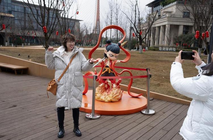 A fan poses for photos with a statue of Nezha, the main character from "Ne Zha 2," at the Gazelle Digital Cultural and Creative Valley in Chengdu, southwest China's Sichuan Province, Feb. 8, 2025. (Xinhua/Jiang Hongjing)