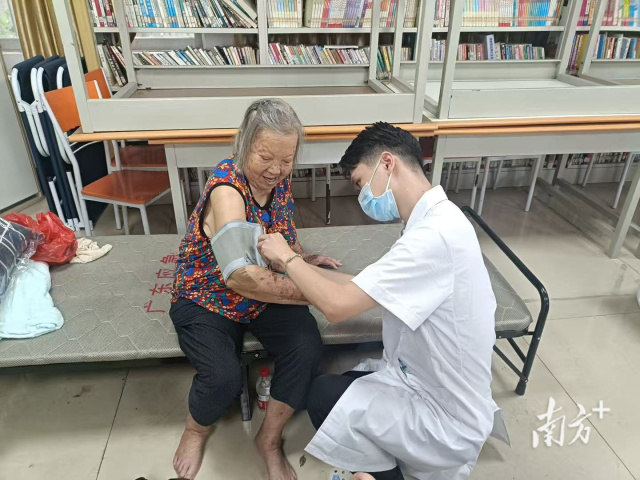 安置点内,医生正在为转移群众测量血压。冯飘洁 摄 安置点内,医生正在为转移群众测量血压。冯飘洁 摄